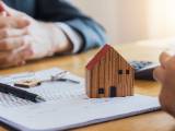 Deux personnes  un bureau autour de documents et d'une maison miniature.