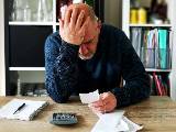 Un homme se prend la tte dans les mains en regardant un document avec une calculatrice  ct. 